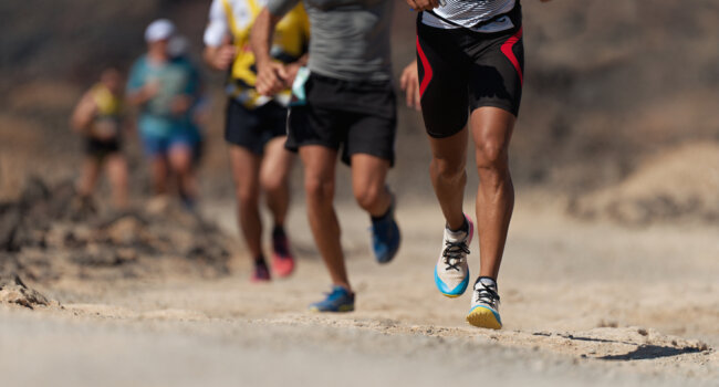 Coureurs participant à une épreuve d’ultra-trail sur terrain naturel accidenté, illustration d’un accident sportif et de l’information sur les assurances couvrant les dommages corporels.